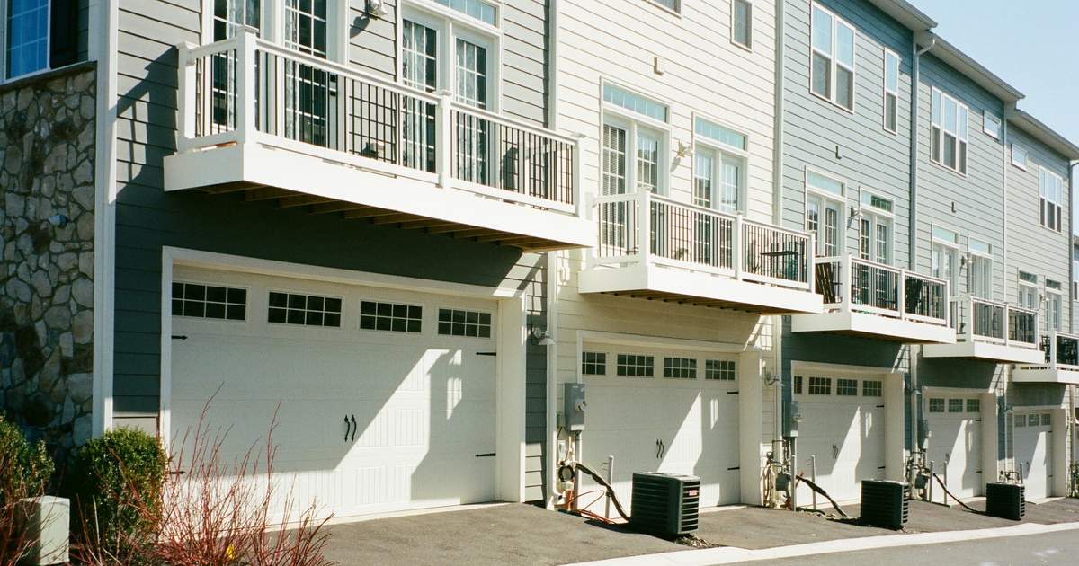 A row of modern townhomes with garages below and balconies above